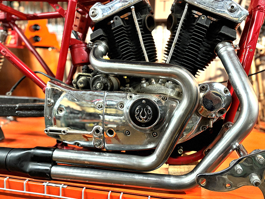 V-Twin Alphabet XL exhaust header set raw finish, shown as a motorcycle exhaust component.